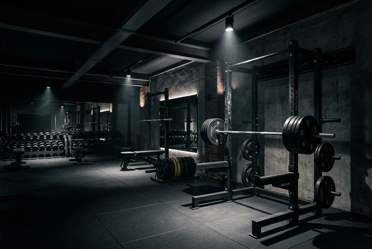 Dark gym with a loaded barbell on a squat rack